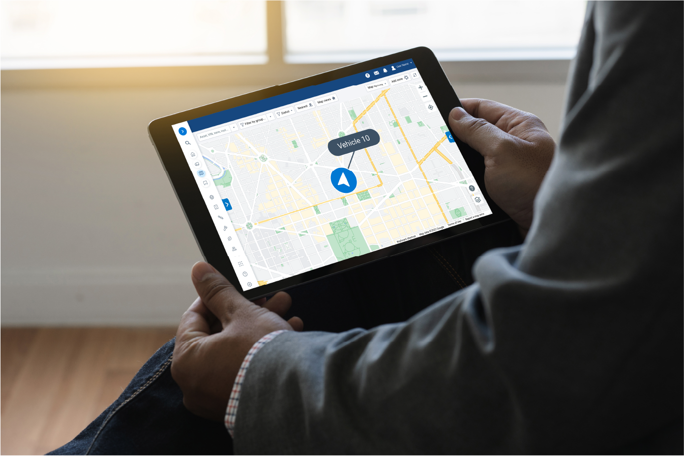 Person holding a tablet displaying a map interface with the label "Vehicle 10" in a blue pin marker, highlighting a specific location.