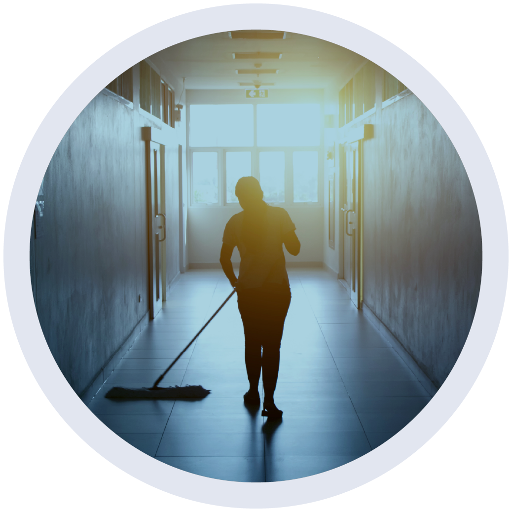 A janitor is walking down an office hallway mopping the tile floors.